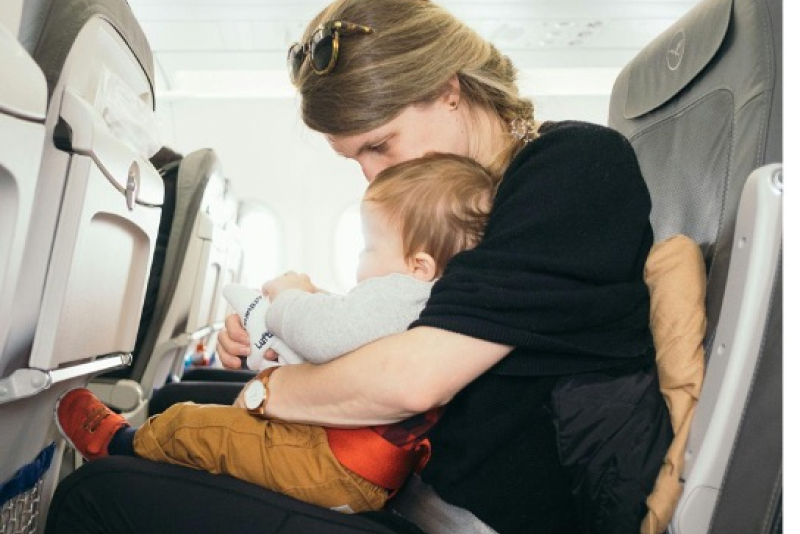 Madre abrazando a su hijo en asiento de avión